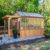 Backyard Discovery Bellerose 11′ x 7′ Cedar Wood and Polycarbonate Walk-In Greenhouse Kit with Pergola, Exhaust Fan, Windows, Hose Hook-Ups, PowerPort, Staging Shelves for Year-Round Outdoor Gardening